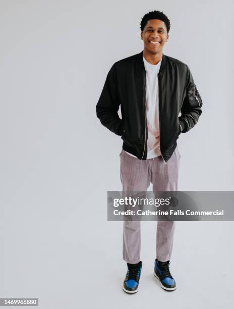 full length portrait of a handsome, young, black man, against a plain white backdrop. - hände in den taschen stock-fotos und bilder