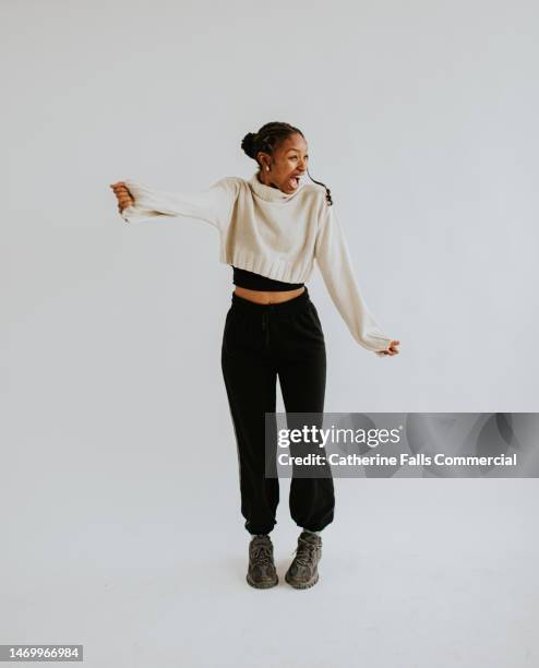 a young black woman adopts various outgoing positions against a white backdrop, emulating performance, movement, dance or presenting - woman full body isolated stock pictures, royalty-free photos & images