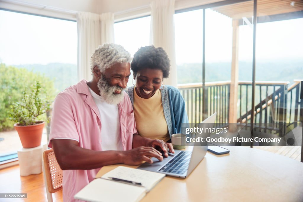 Lächelndes Paar erledigt seine Finanzen auf einem Laptop zu Hause