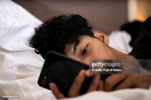 asian young men using smartphones in bed - young man to bed photos et images de collection