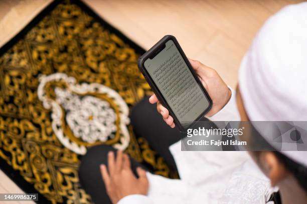 reading quran on smartphone apps - fajrul islam stock pictures, royalty-free photos & images