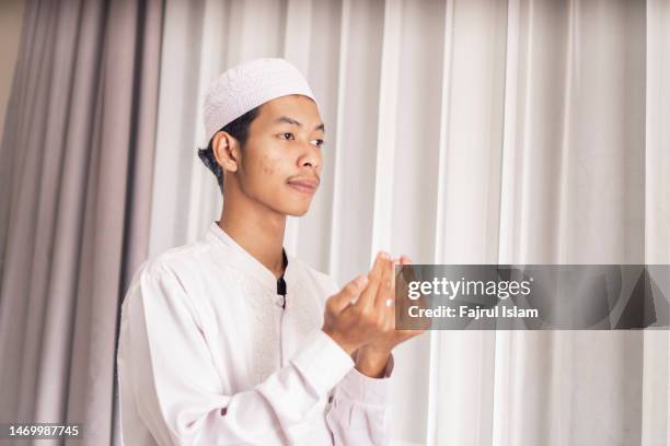 muslim man with open palm praying at home during month of ramadan - namaz stock pictures, royalty-free photos & images