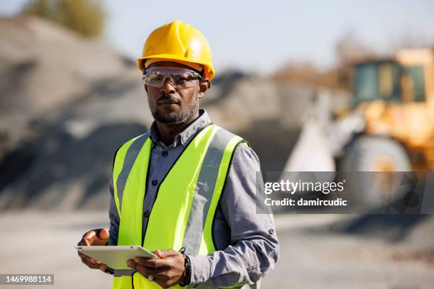 portrait of male engineer with digital tablet at building site - miner portrait stock pictures, royalty-free photos & images