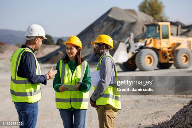 ingenieros discutiendo en el sitio de construcción - pala-parte-de-un-vehículo fotografías e imágenes de stock