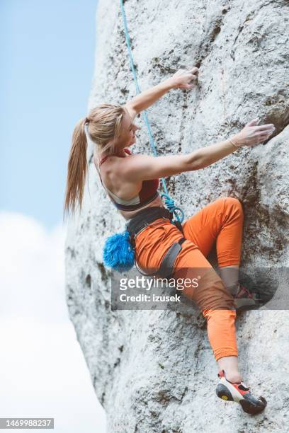 athletic woman climbing on cliff rock - clambering stock pictures, royalty-free photos & images