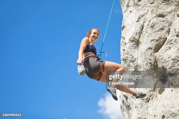 young woman climbing on cliff rock - clambering stock pictures, royalty-free photos & images