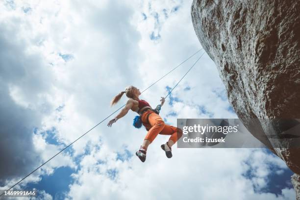 young woman hanging on rope while climbing - extreme sports equipment stock pictures, royalty-free photos & images