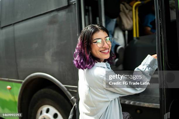 portrait of young woman getting on the bus - autocarro de turismo imagens e fotografias de stock