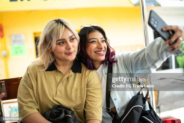 young women taking a selfie using mobile phone on a open-air bus - open top bus stock pictures, royalty-free photos & images