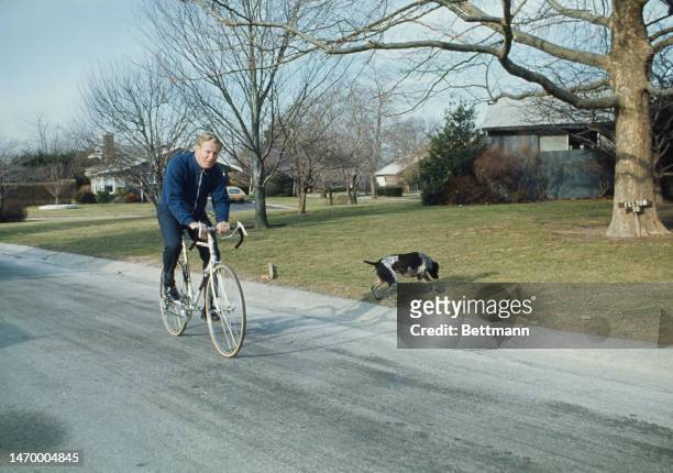 Edward 'Whitey' Ford rides a bike near his home in Lake Success, New York, as his dog Snoopy follows him down the street on Januar 25th, 1974. Ford,...