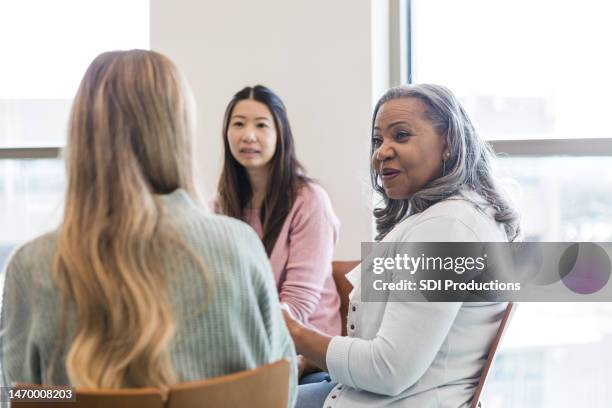 unrecognizable young woman listens to advice from female therapist - group therapy stock pictures, royalty-free photos & images