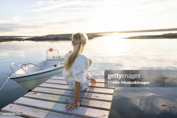 woman contemplates reflection on the lake at sunset - sjöstrand bildbanksfoton och bilder