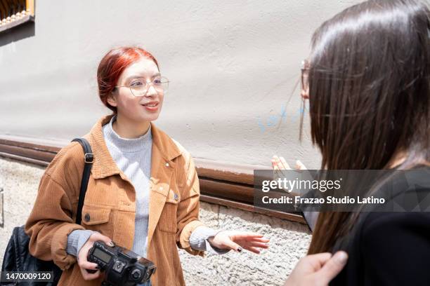 young female tourist asking someone for direction outdoors - tourist asking stock pictures, royalty-free photos & images