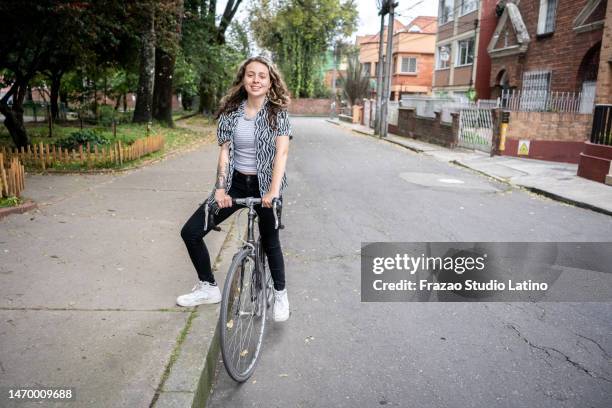 portrait of a young woman riding a bike at street - bogota 個照片及圖片檔