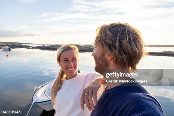 couple relaxing on pier above lake at sunset - boat scandinavia stock pictures, royalty-free photos & images