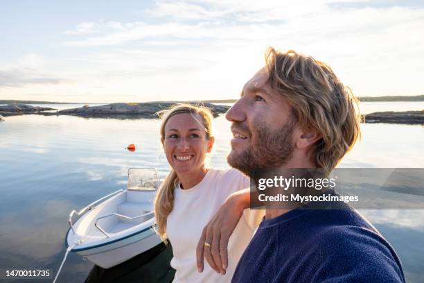couple relaxing on pier above lake at sunset - scandinavische cultuur stockfoto's en -beelden