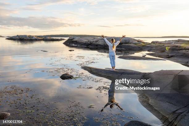 woman contemplates reflection on the lake at sunset - arms outstretched bildbanksfoton och bilder