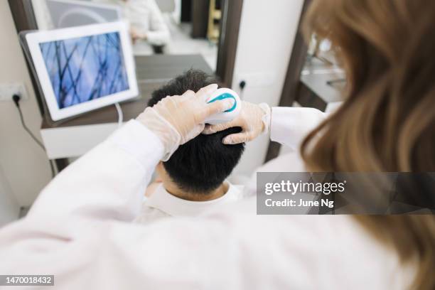 hair therapist is checking a man's scalp. - human scalp stock pictures, royalty-free photos & images