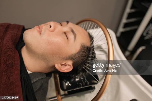 un hombre asiático está disfrutando de su spa de cabello. - cuero cabelludo fotografías e imágenes de stock