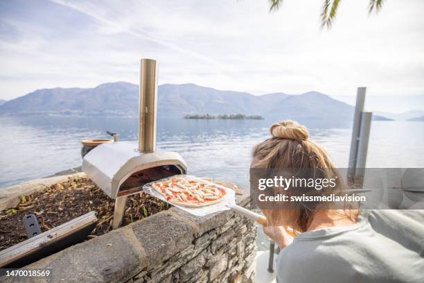 woman baking pizza at home in her garden, wood fire pizza oven - pizzaugn bildbanksfoton och bilder