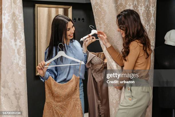 giovane donna che aiuta la sua amica a provare un vestito da ballo nella boutique - camerino di prova foto e immagini stock