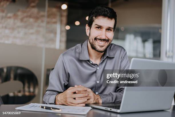 business man looking at camera beside laptop - digital devices beside each other bildbanksfoton och bilder