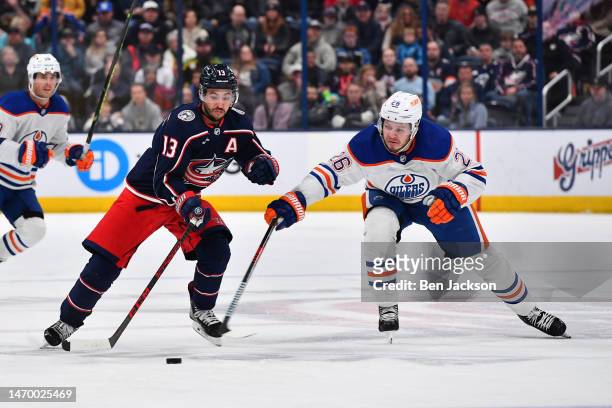 Johnny Gaudreau of the Columbus Blue Jackets and Mattias Janmark of the Edmonton Oilers reach for a loose puck during the third period of a game at...