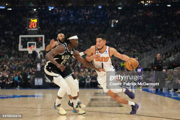 Devin Booker of the Phoenix Suns dribbles the ball against Jrue Holiday of the Milwaukee Bucks in the first half at Fiserv Forum on February 26, 2023...