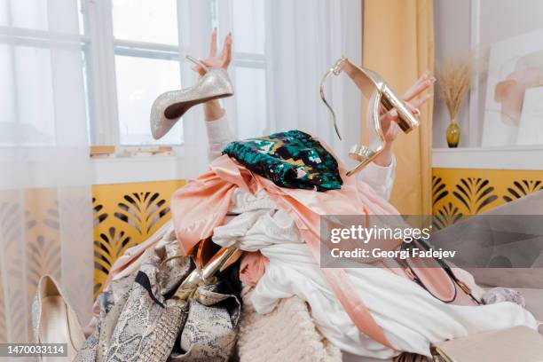 woman hands out of a pile of clothes and accessories on the floor. too much shopping. shopaholic girl. shopping addiction concept. - kaufsucht stock-fotos und bilder