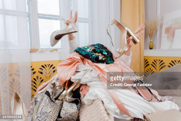 woman hands out of a pile of clothes and accessories on the floor. too much shopping. shopaholic girl. shopping addiction concept. - shopaholic woman stock pictures, royalty-free photos & images