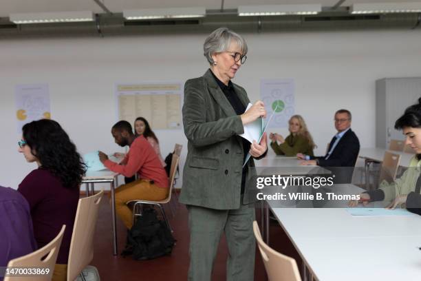 teacher handing out study material to mature students - germany womens training session stock pictures, royalty-free photos & images