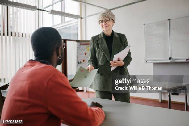 teacher handing student test result - man handing paper stock pictures, royalty-free photos & images