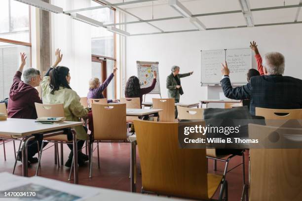 mature students with hands raised in classroom - germany womens training session stock pictures, royalty-free photos & images