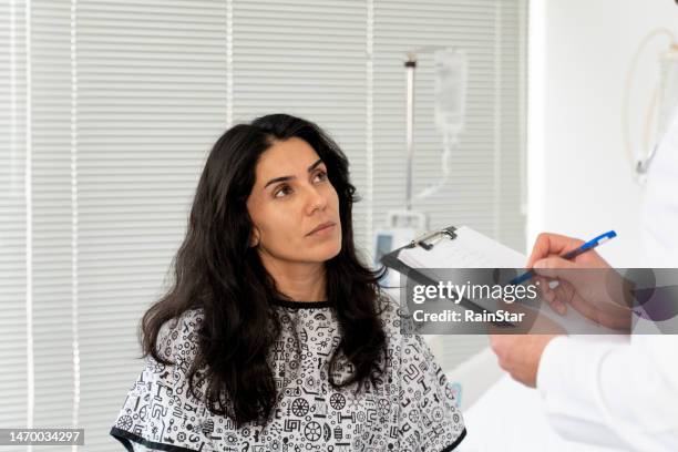 patiente assise sur une table d’examen dans le cabinet du médecin - blouse dexamen médical photos et images de collection