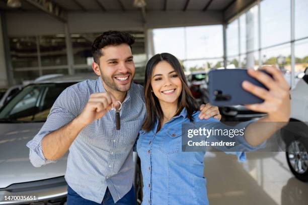 feliz pareja comprando un coche y tomándose una selfie sosteniendo las llaves - car ownership fotografías e imágenes de stock