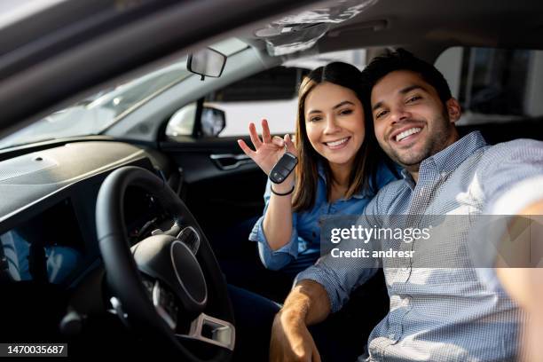 pareja feliz sentada en su nuevo auto y sosteniendo las llaves - auto nuevo fotografías e imágenes de stock