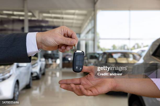 car salesperson giving the keys to a client buying a car at the dealership - test drive stock pictures, royalty-free photos & images