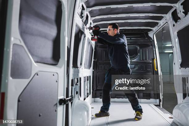 converting a van into a home on wheels. man working with a battery-powered drill inside a van. - broca imagens e fotografias de stock