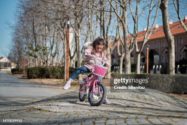 little girl falling off bicycle - off balance stockfoto's en -beelden