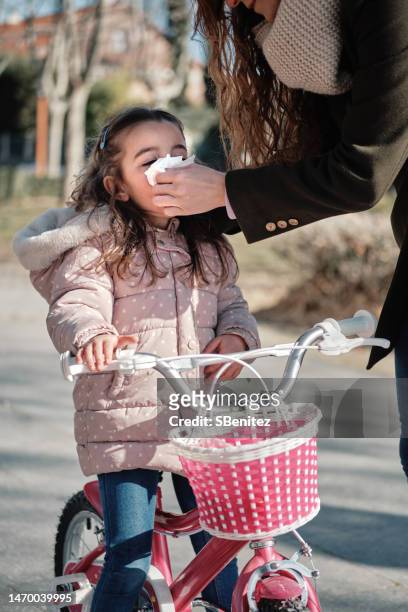 mother wiping nose of daughter with tissue - bicycle basket stock pictures, royalty-free photos & images