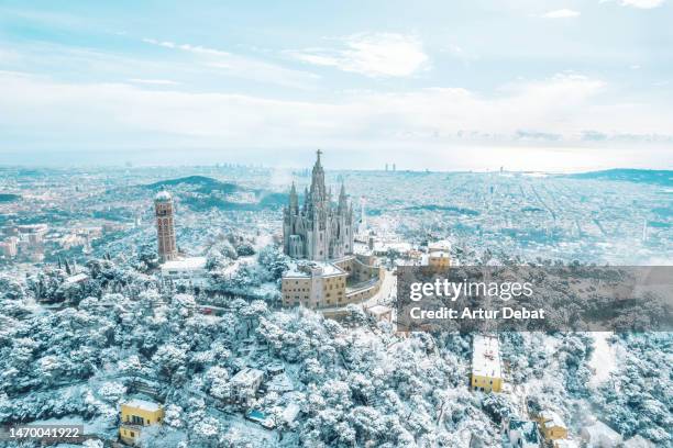 aerial view of the barcelona tibidabo mountains covered in snow with the barcelona city skyline after snowfall during winter of 2023. - fairytale village stock pictures, royalty-free photos & images