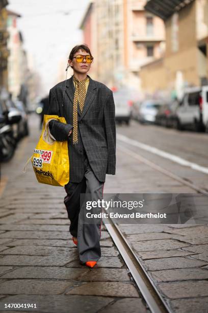 Guest wears a silver long chain pendant earring, yellow sunglasses, a yellow tulle t-shirt, a black with blue and yellow fish print pattern silk...