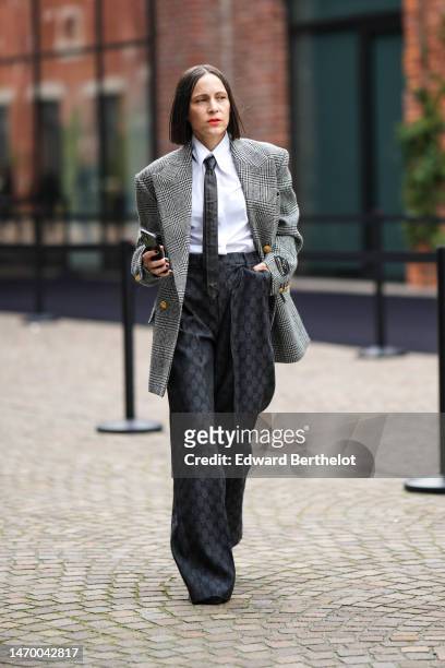 Guest wears a white shirt, a black tie, a black and white houndstooth print pattern oversized blazer jacket, a black with GG monogram embroidered...