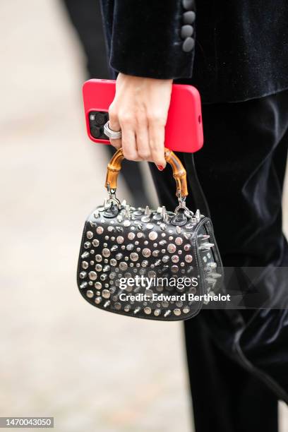 Guest wears a black velvet blazer jacket, black velvet large pants, a black shiny leather with silver nailed / studded handbag from Gucci, a large...