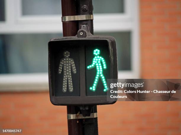 green traffic light at a pedestrian crossing in paris - voetgangersoversteekplaats bord stockfoto's en -beelden