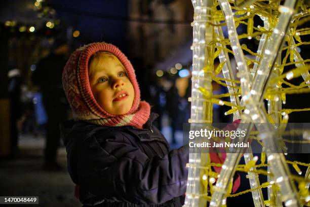 kleines mädchen, das sich die weihnachtsbeleuchtung anschaut - skimaske stock-fotos und bilder