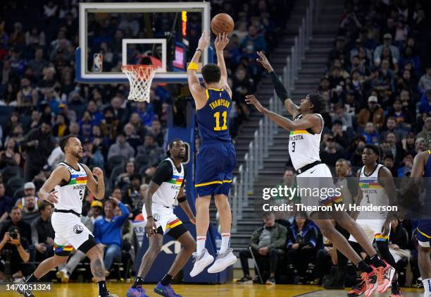 Klay Thompson of the Golden State Warriors shoots over Jaden McDaniels of the Minnesota Timberwolves during the first quarter of an NBA basketball...