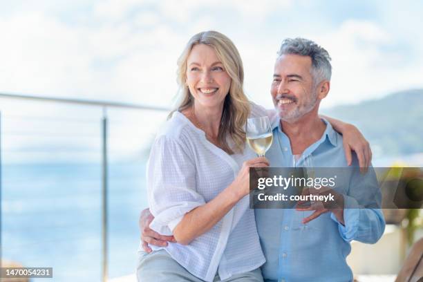 mature couple drinking and toasting with wine. they are embracing with the woman on the mans knee. - old couple restaurant stockfoto's en -beelden