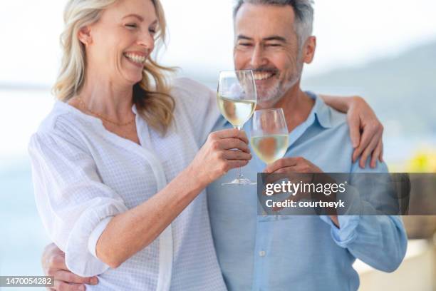 mature couple drinking and toasting with wine at a waterfront hotel or home - embarcação comercial imagens e fotografias de stock