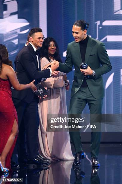 Virgil van Dijk shakes hands with Jermaine Jenas after being presented with their trophy after being included in the FIFA FIFPRO Men's World 11 2022...